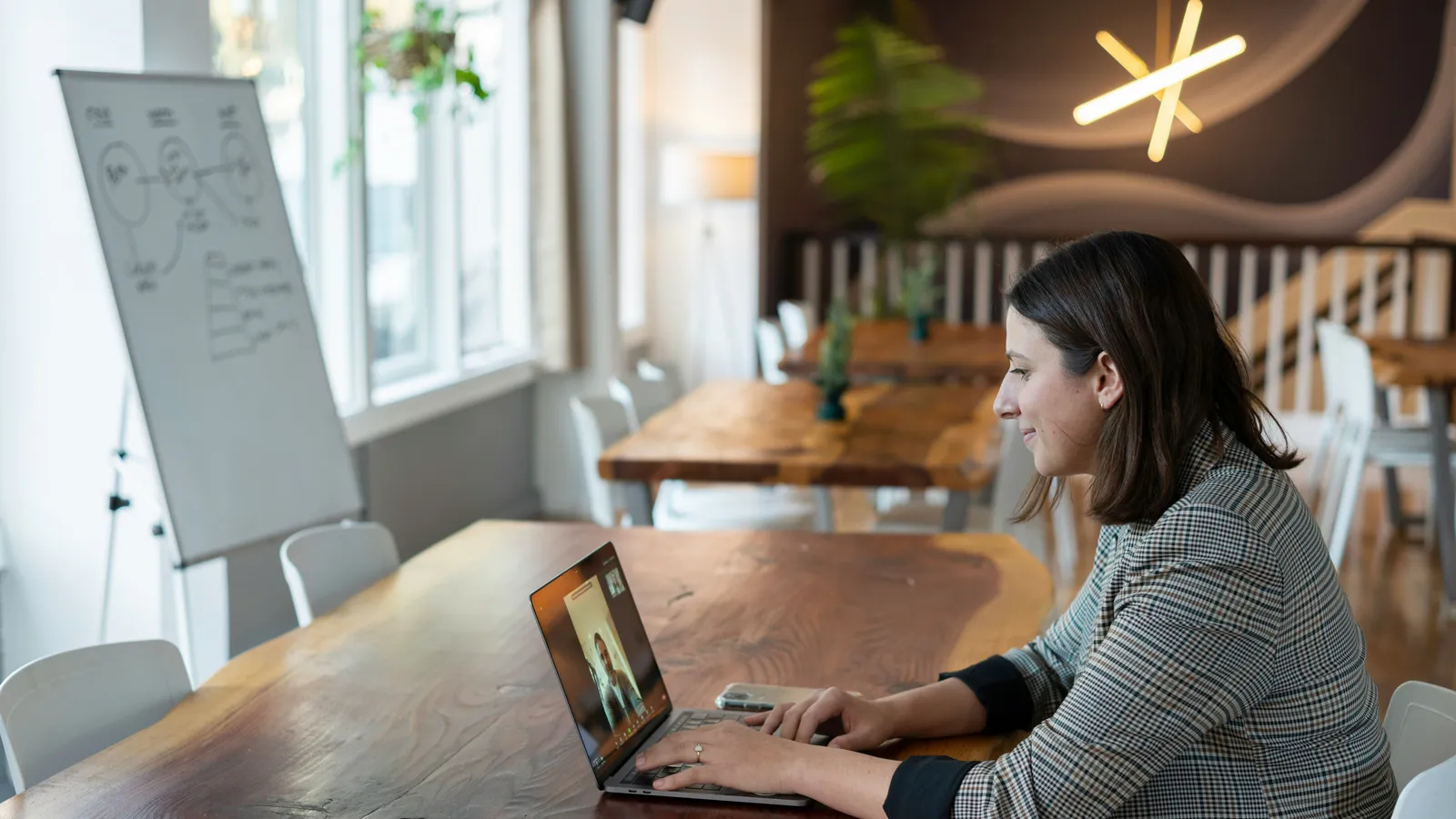 Frau arbeitet konzentriert am Laptop an einem Holztisch in einem hellen Büro